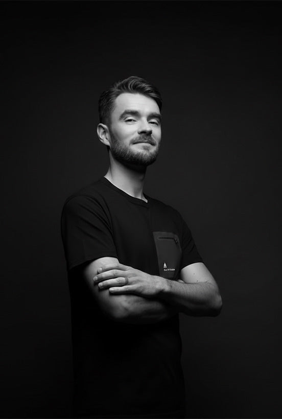 Founder Charly, standing with arms crossed, wearing a black t-shirt from the Elyzion collection